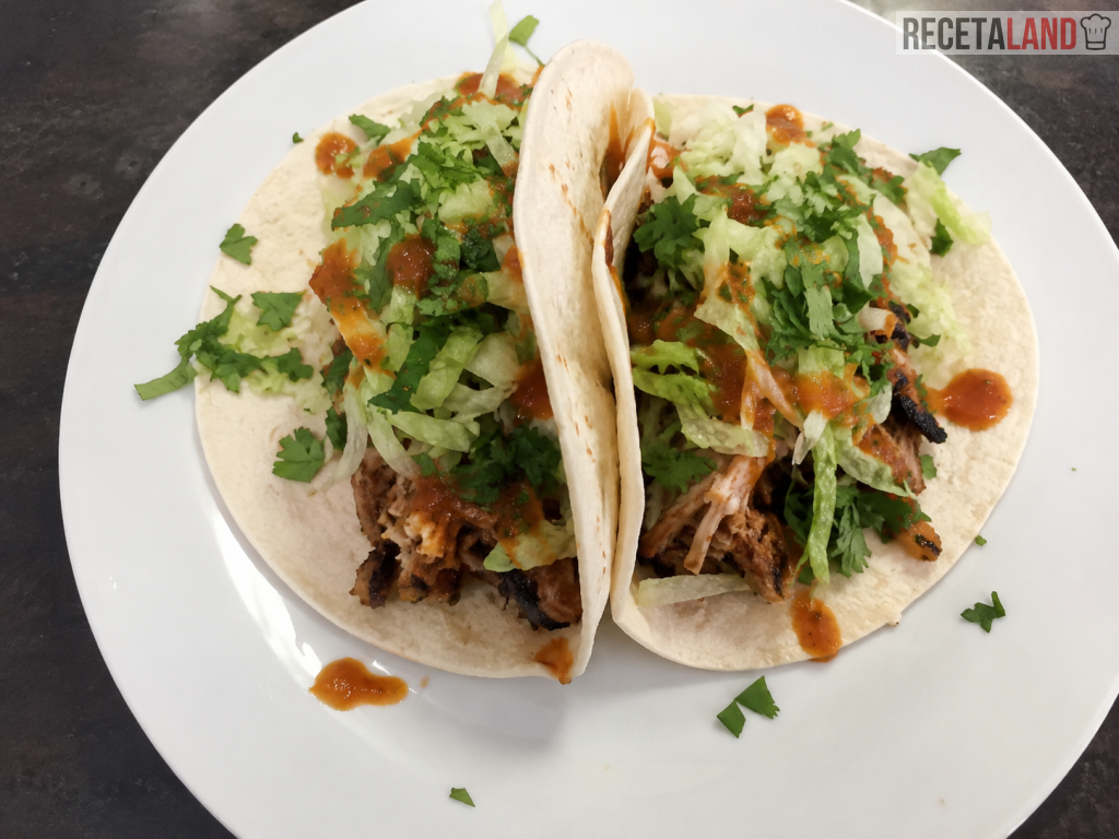 Tinga de pollo con chorizo servida en tacos con lechuga, queso y salsa picante