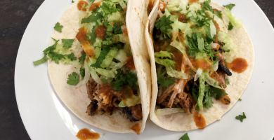 Tinga de pollo con chorizo servida en tacos con lechuga, queso y salsa picante