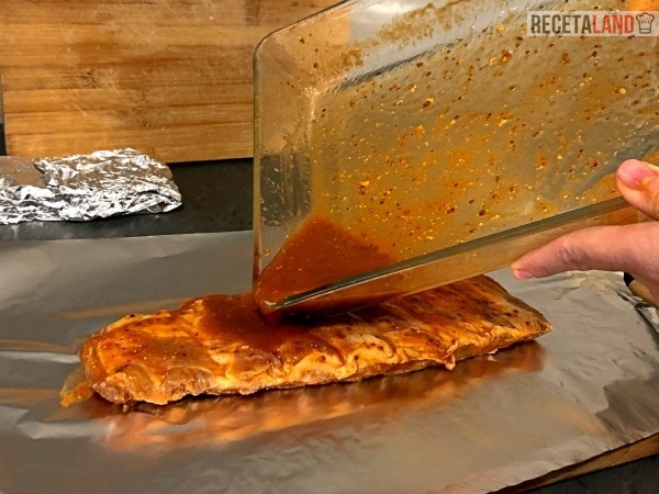 echando la salsa en el costillar en papel de aluminio antes de cerrar y meter al horno