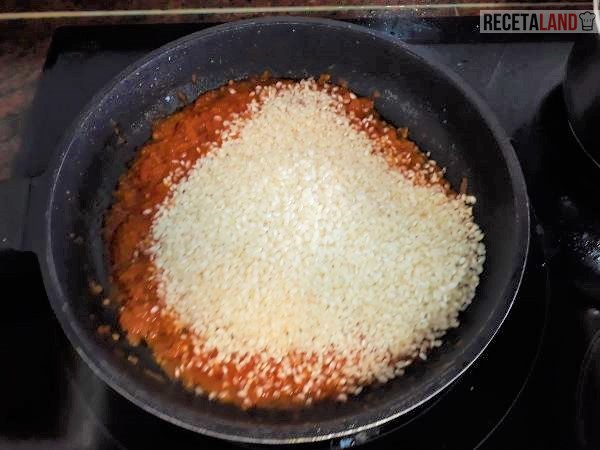 Añadiéndole el arroz para mezclarlo con el tomate