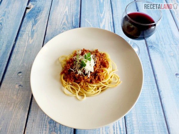 Espaguetis con carne picada acompañados de una copa de vino tinto