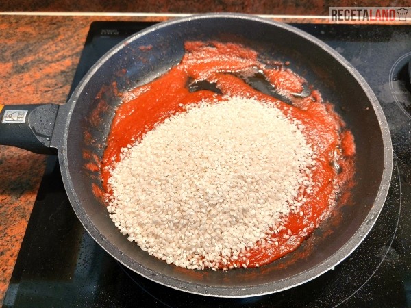 Echando el arroz para mezclarlo con el tomate